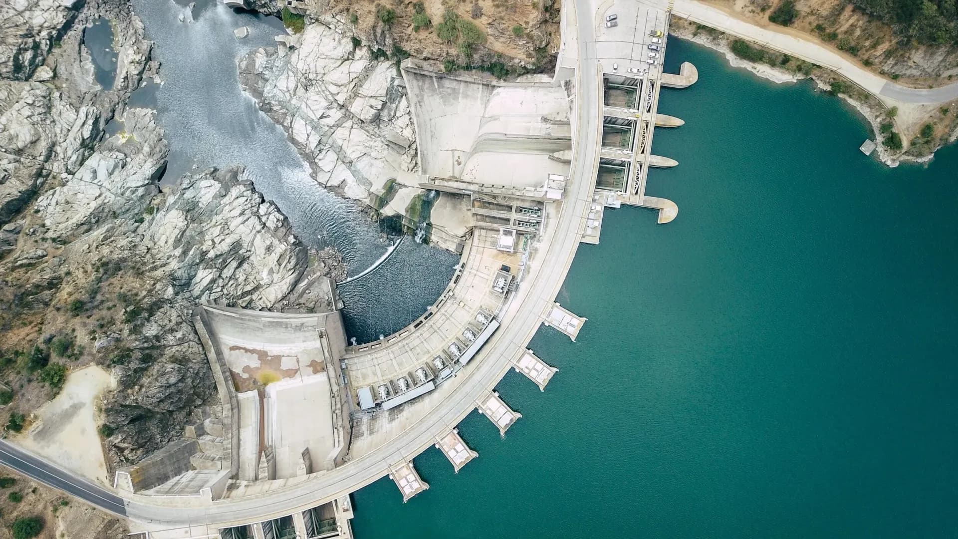Drone view looking down on a concrete arch dam and spillway